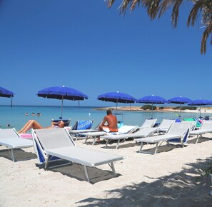 Una spiaggia con lettini e ombrelloni blu.