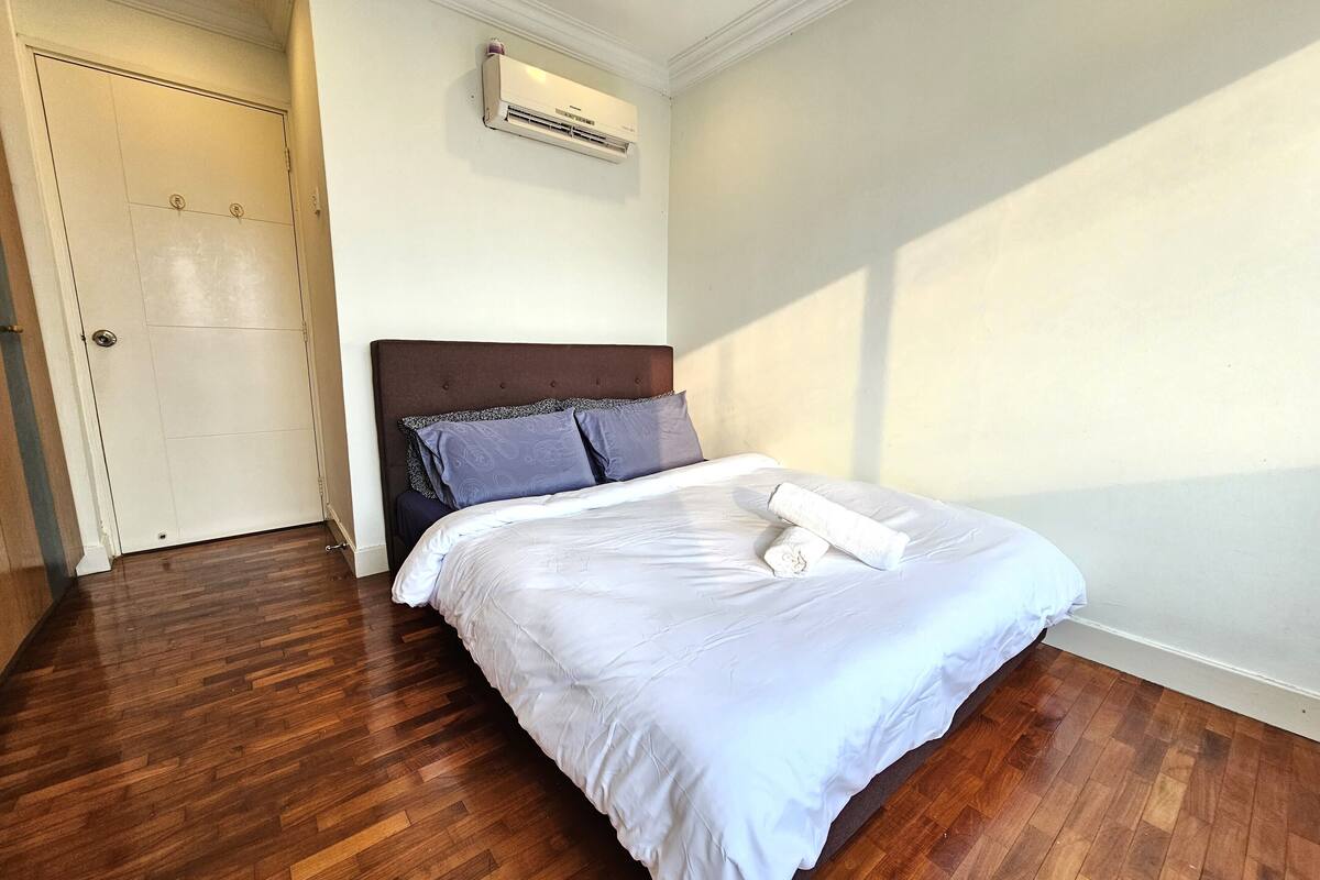 A neatly made bed with white linens, a dark headboard, and two pillows.