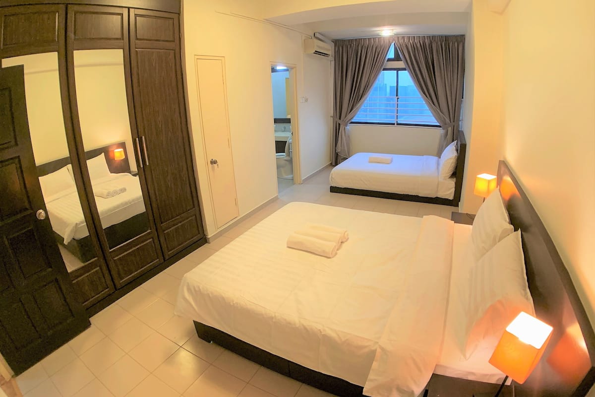 A hotel room with a large bed, a wardrobe, a bathroom, and a view of the city through the window.