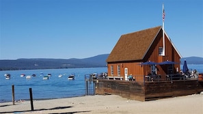 A wooden building with a sloped roof near a body of water, surrounded by boats.