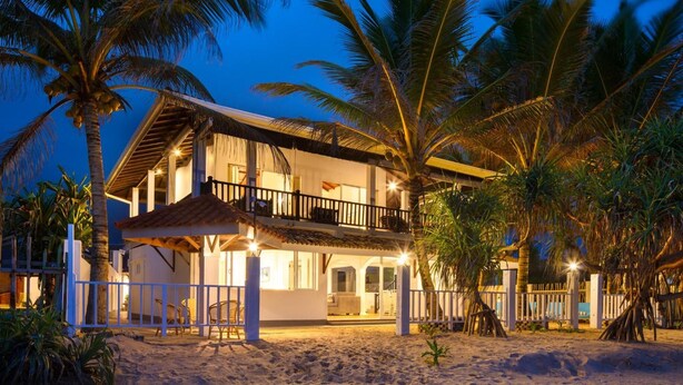 A beachfront property with a two-story building, a balcony, and a covered outdoor seating area. - Villa Mer Vue (Madampagama)