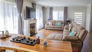 A living room with a fireplace, a sofa set, a television, and a dining table with teaware.
