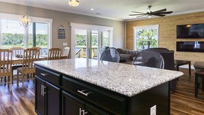 Una cocina moderna con encimeras de granito, armarios de madera e iluminación colgante.