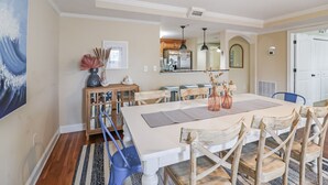Un comedor con una mesa grande, sillas de madera y un armario con puertas de cristal.