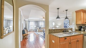 Amplia sala de estar con cocina, armarios de madera y un espejo grande.