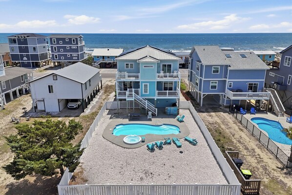 A beachfront property with a swimming pool, multiple buildings, and a view of the ocean.