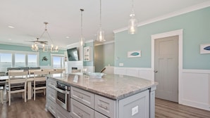 A modern kitchen with a central island, stainless steel appliances, and pendant lighting.