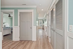 A hallway with a wooden floor, white doors, and a ceiling fan.
