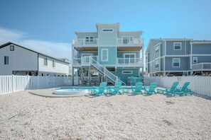 A beachfront property with a pool, multiple levels, and a white fence.