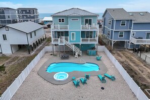 Een tweelaags huis met een zwembad, buitenmeubilair en uitzicht op de oceaan.