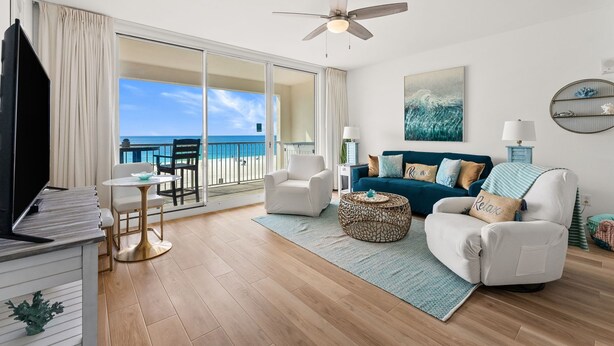 A spacious living room with a view of the ocean, a ceiling fan, a sofa, a coffee table, and a TV. - Welcome to MAJESTIC-PEARL! Newly renovated in 2026!  
2nd Floor BEACHFRONT! (Panama City Beach)