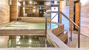 A modern indoor pool area with a clear water surface, a wooden floor, and a metal staircase leading to a door. -  Anshin oyado Woman & Man Nagoya (Nagoya)