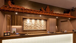 A reception desk with a wooden finish, a decorative wall panel, and a patterned floor. -  Anshin oyado Woman & Man Nagoya (Nagoya)