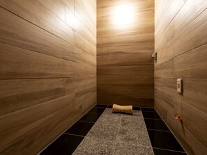A modern bathroom with wooden walls, a black tiled floor, and a small towel on the floor. -  Anshin oyado Woman & Man Nagoya (Nagoya)