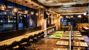 A modern restaurant with a long counter, multiple seating areas, and a view of the cityscape through large windows. -  Anshin oyado Woman & Man Nagoya (Nagoya)
