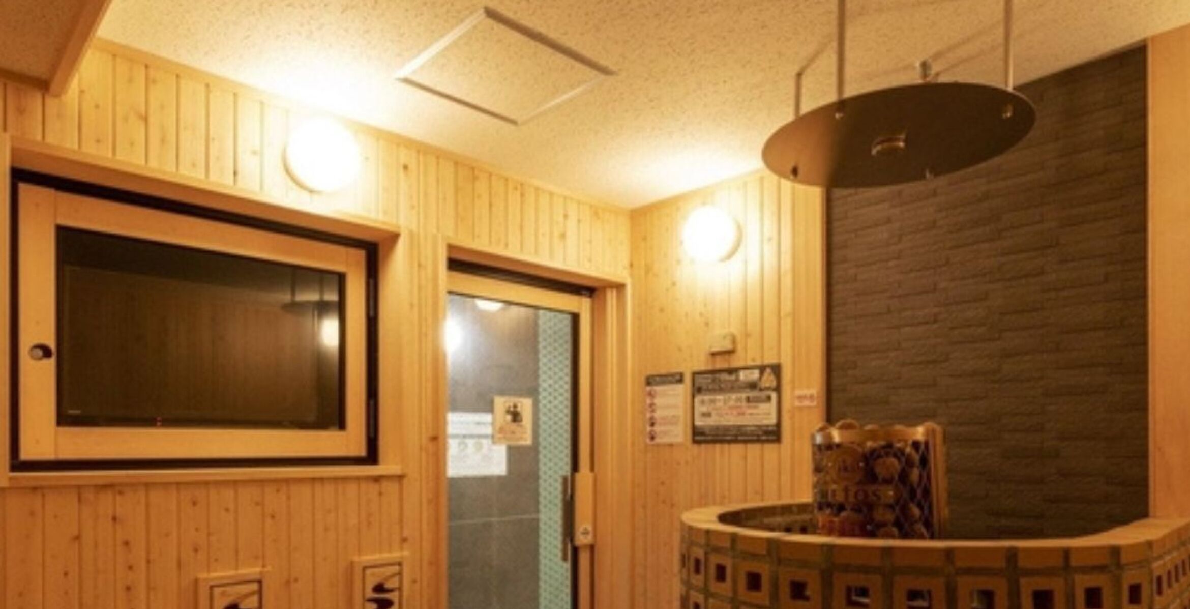 A wooden interior with a reception desk, a large window, and a wall-mounted light fixture.