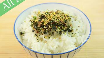 A bowl of white rice topped with green seaweed and sesame seeds.