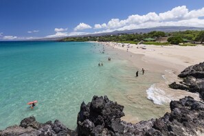 A beach with clear turquoise water, rocky shoreline, and a sandy beach with people and umbrellas. - SUMMER VACA ALOHA!  Steps to the Ocean, Puako "Dream House" (Kamuela)