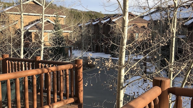 En træterrasse med gelænder, udsigt over et sneklædt landskab og bygninger.