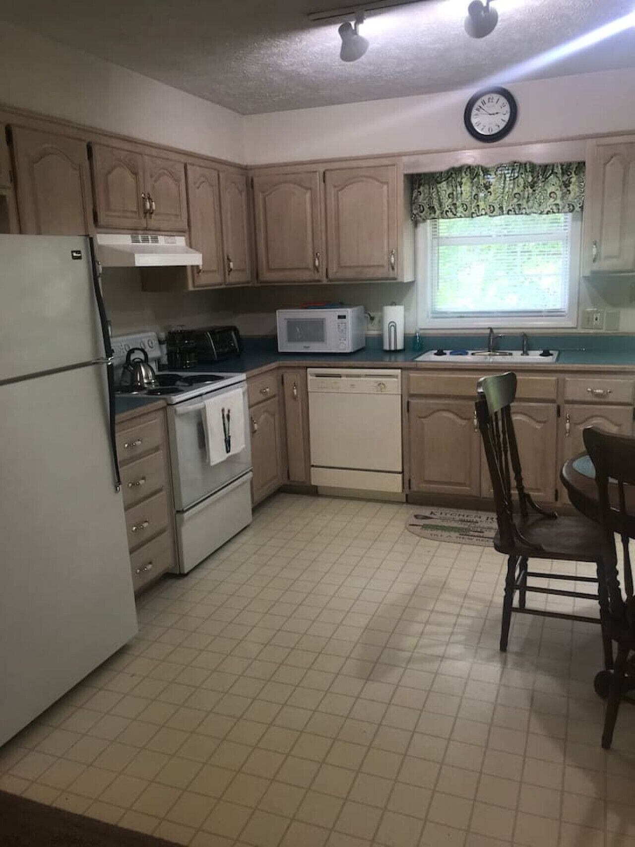 A compact kitchen with wooden cabinets, a microwave, a stove, and a sink.
