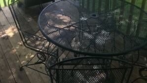 A deck with a grill and a metal table and chairs.
