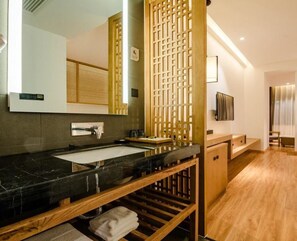 A modern bathroom with a wooden vanity, a large mirror, and a built-in sink.
