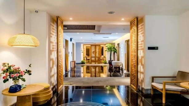 A modern hotel lobby with a polished floor, a reception desk, and a seating area.