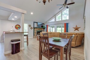A spacious living area with a dining table, wooden chairs, a sofa, and a fireplace. - Shootout Weekend Finds Room to Spread Out (Osage Beach)