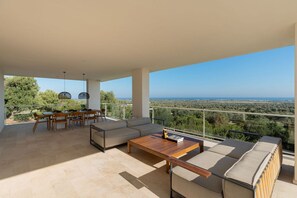 A spacious balcony with a dining area, seating, and a view of the landscape.
