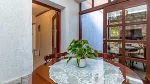 Un coin repas avec une table en bois, une nappe en dentelle et une plante en pot.
