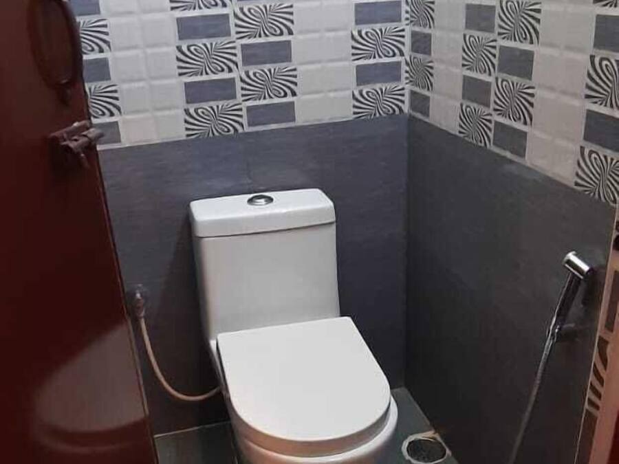 Un baño pequeño con inodoro, ducha y pared de azulejos con un diseño geométrico.