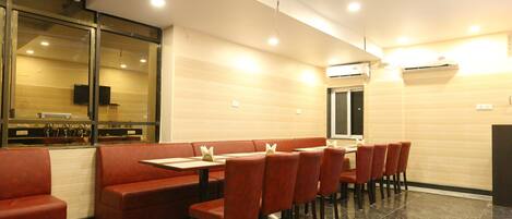 A restaurant with red booths and tables, a tiled floor, and an air conditioning unit on the wall.
