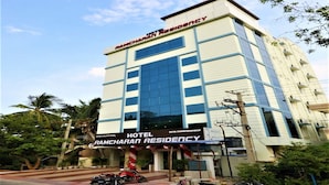 Um edifício de hotel com vários andares e uma placa com a inscrição 'RAMCHARAN RESIDENCY HOTEL'.