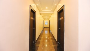 Um corredor comprido e estreito com piso lustroso e portas em ambos os lados.
