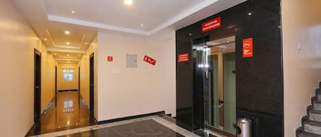 A hotel lobby with a marble floor, a staircase, and emergency exit signs.