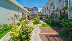 Un patio con un sendero sinuoso, vegetación y un parque infantil.