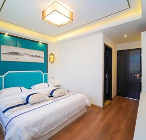 A modern bedroom with a bed, a wall-mounted light, and a door.