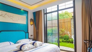 Un dormitorio moderno con una cama grande, vistas del jardín a través de un cristalero corredero y una pared de acento azul.