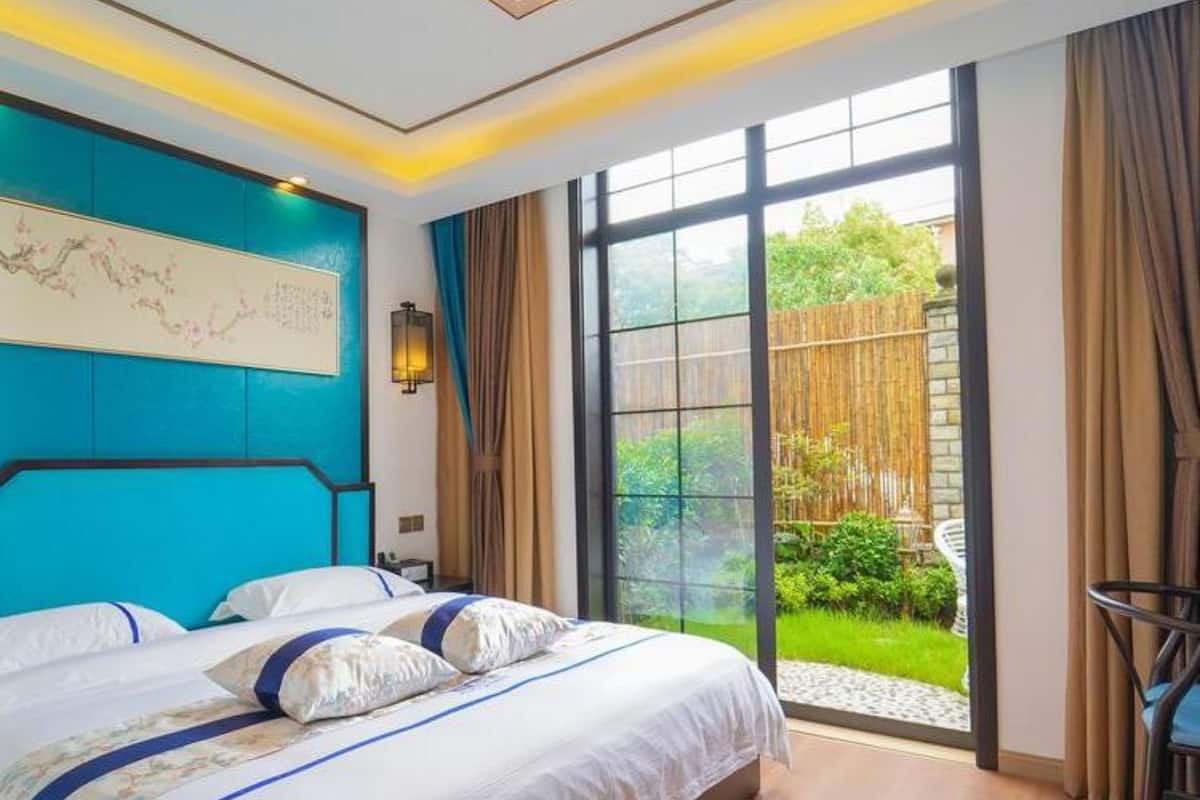 Un dormitorio moderno con una cama grande, vistas del jardín a través de un cristalero corredero y una pared de acento azul.