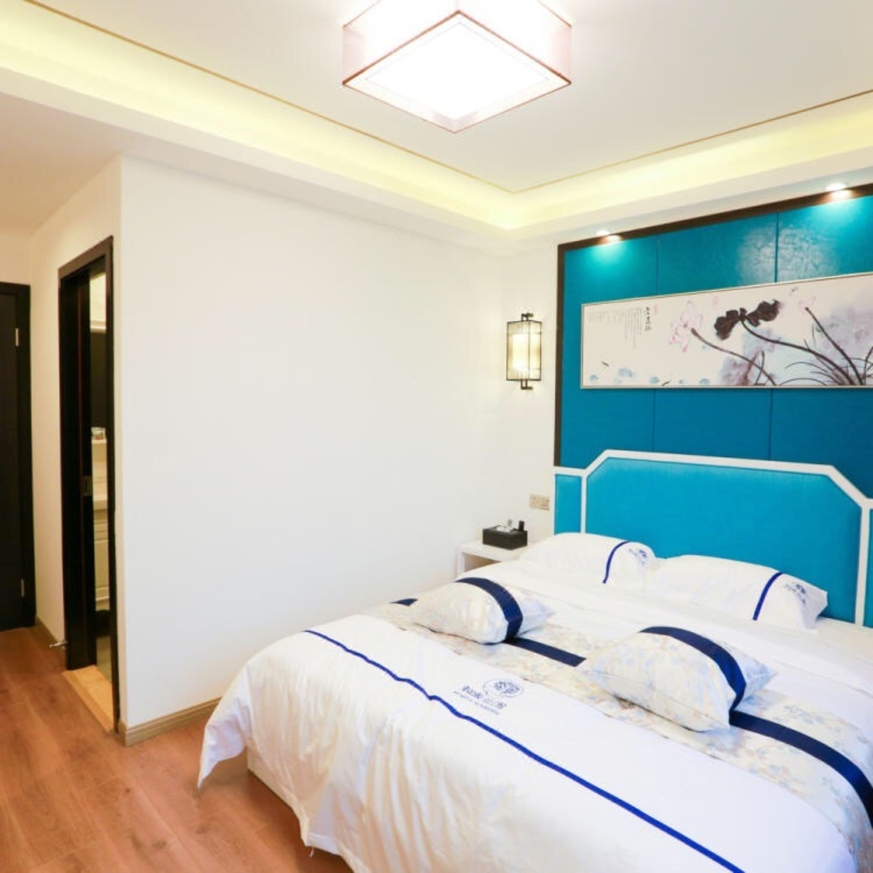 Una camera da letto con un letto, un comodino, una lampada a parete e un quadro.