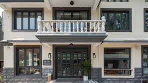 Un edificio de dos plantas con balcón, ventanas amplias y fachada de piedra.