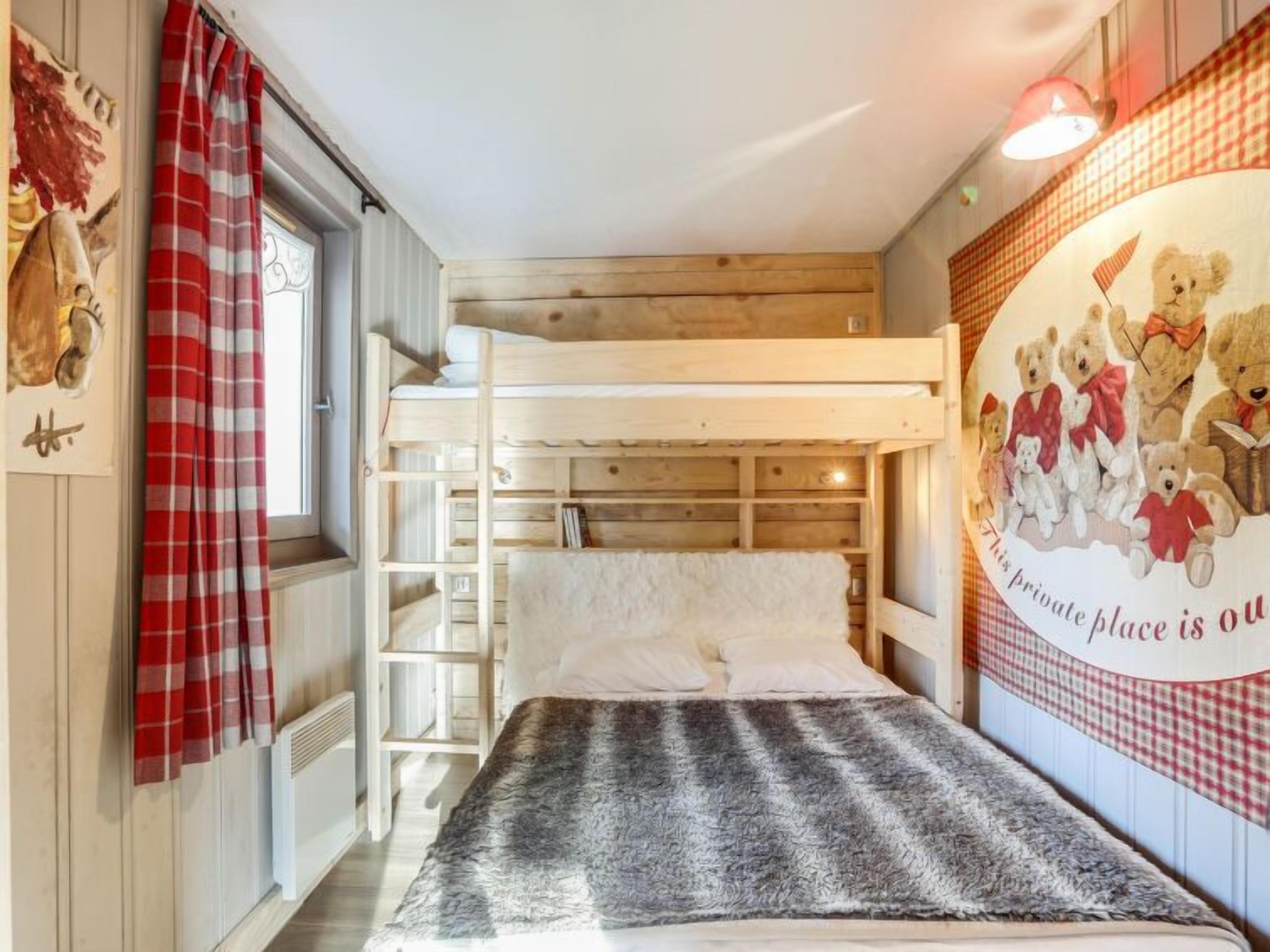 A bunk bed room with a red and white checkered curtain, a fluffy grey blanket, and a wall mural of teddy bears.