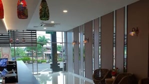 A hotel lobby with a reception desk, seating area, and large windows offering a view of the outdoors. - Ants Hotel (Kangar)