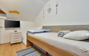 Relax in a serene bedroom with a neatly made bed, wooden headboard, and flat-screen TV.