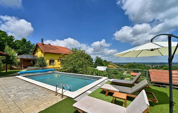 Relax by the pool surrounded by lush greenery and a hilly view.