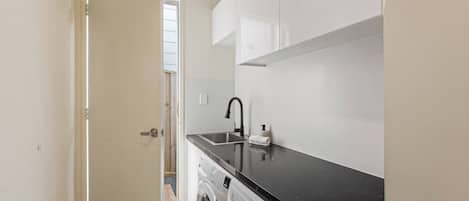 A compact laundry area with a washing machine, a sink, and a countertop.