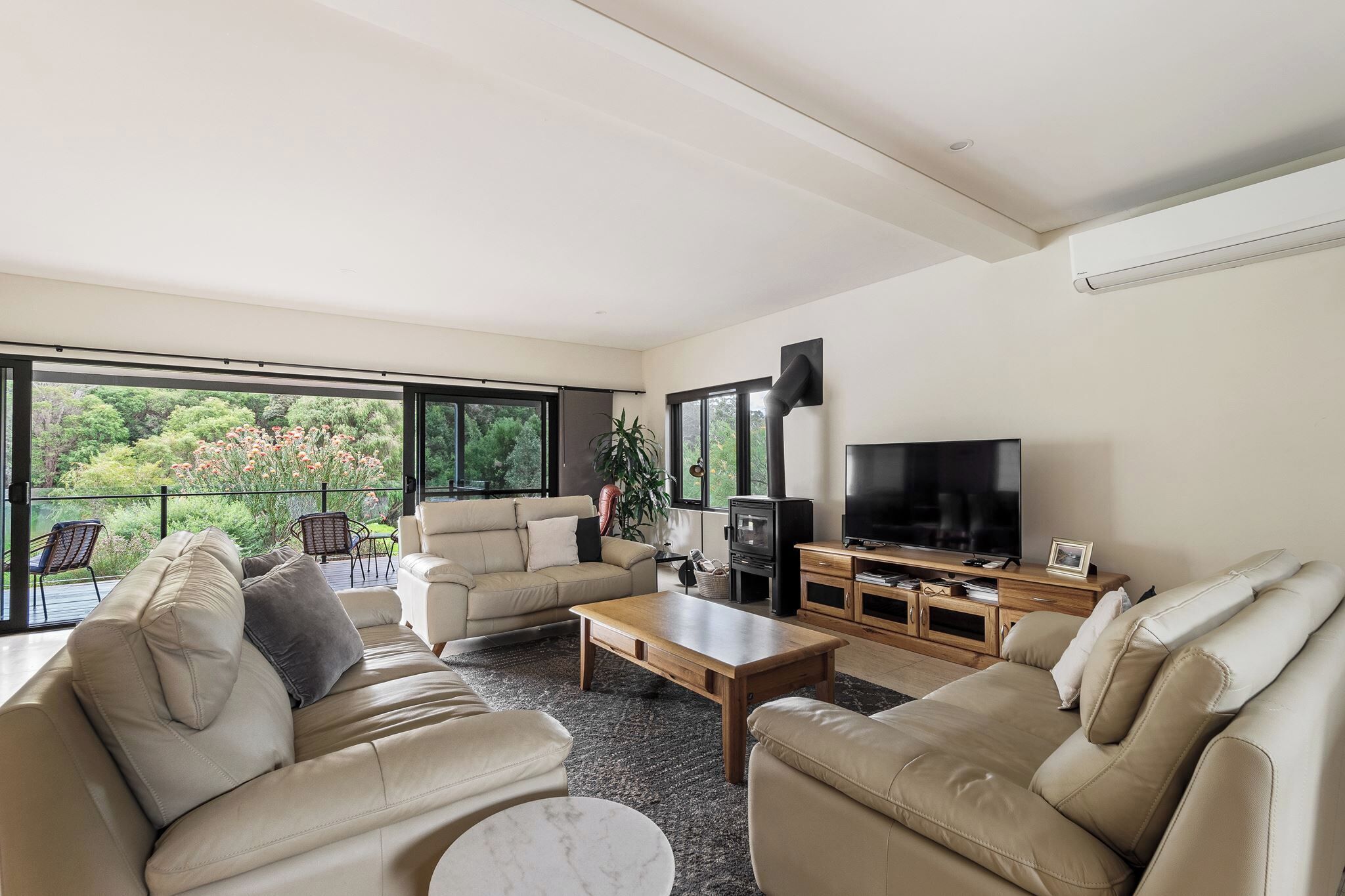 Ein modernes Wohnzimmer mit einer Couch, einem Couchtisch und einem Fernseher auf einem Holzgestell.