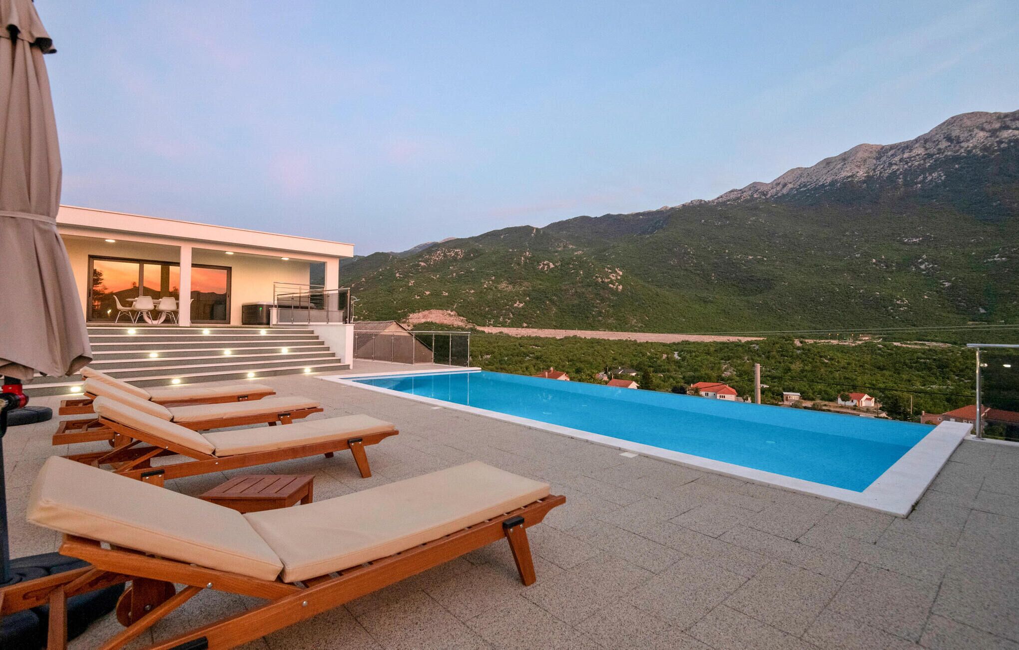 A rooftop pool area with lounge chairs and a view of mountains.