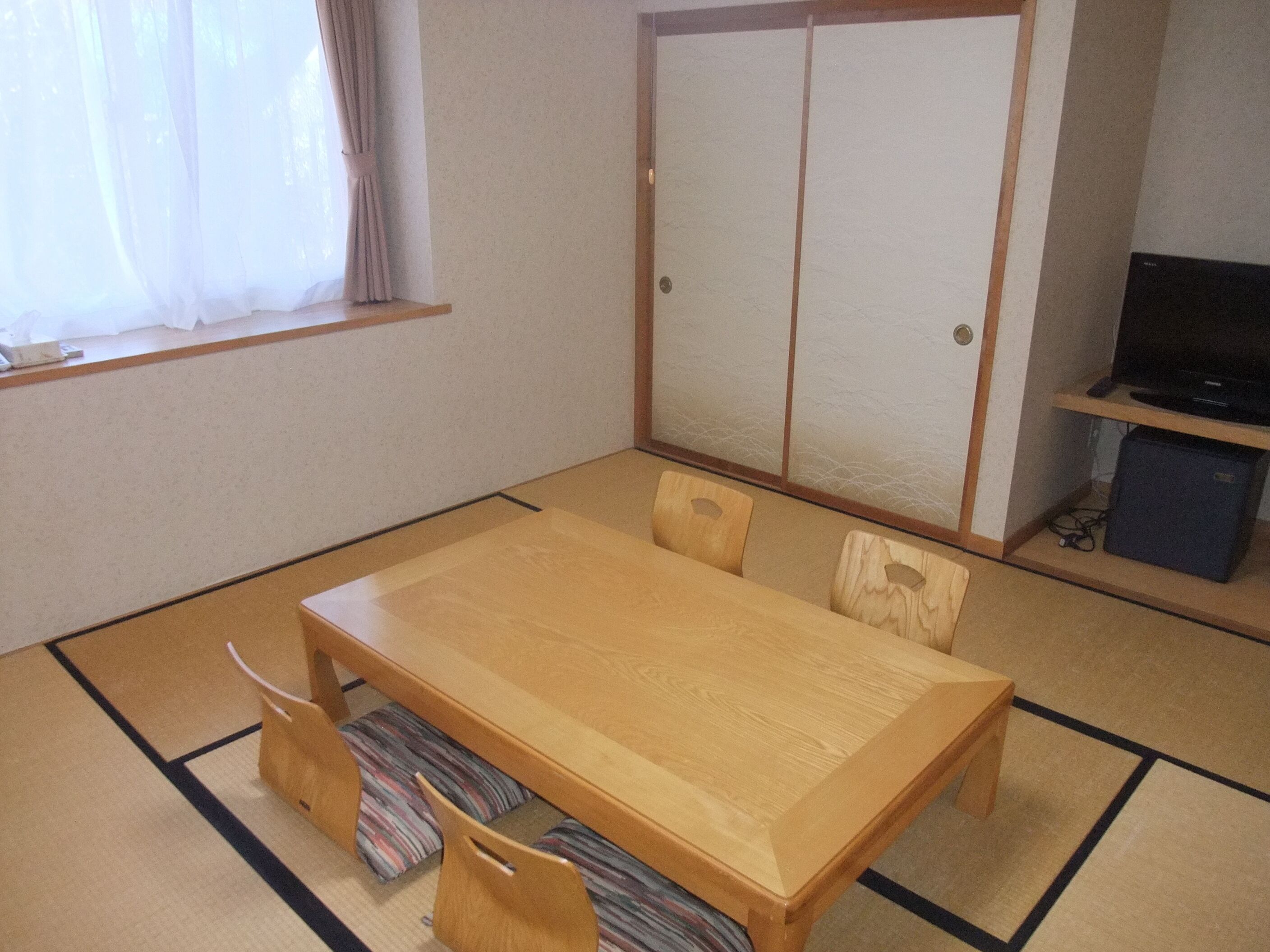 A traditional Japanese-style room with tatami flooring, a low wooden table, and a sliding door closet.
