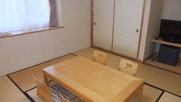 A traditional Japanese-style room with tatami flooring, a low wooden table, and a sliding door closet.